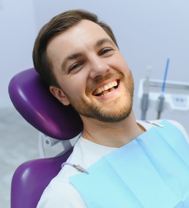 Happy male patient in purple dental chair after deep cleaning treatment at Burbank dental office.