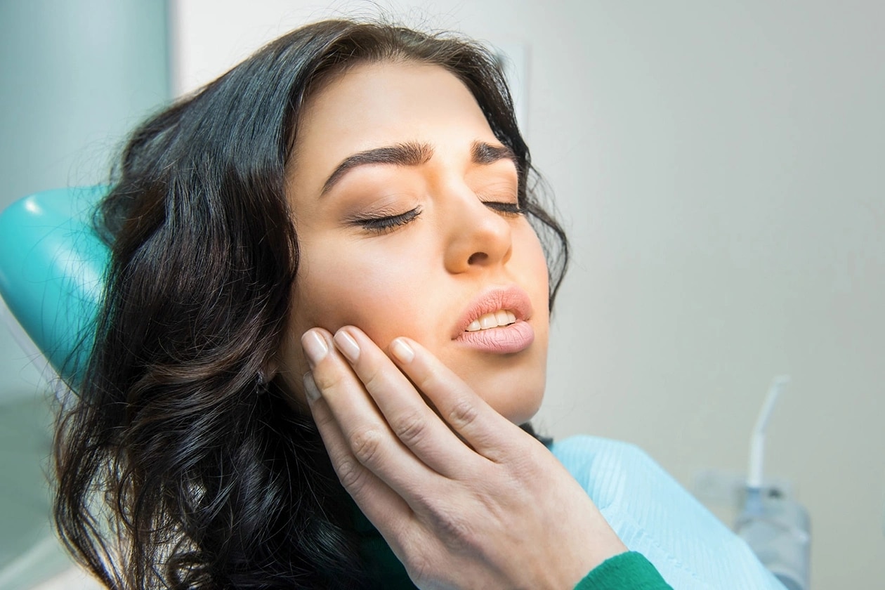 Woman experiencing TMJ pain in dental chair at Burbank dental practice.