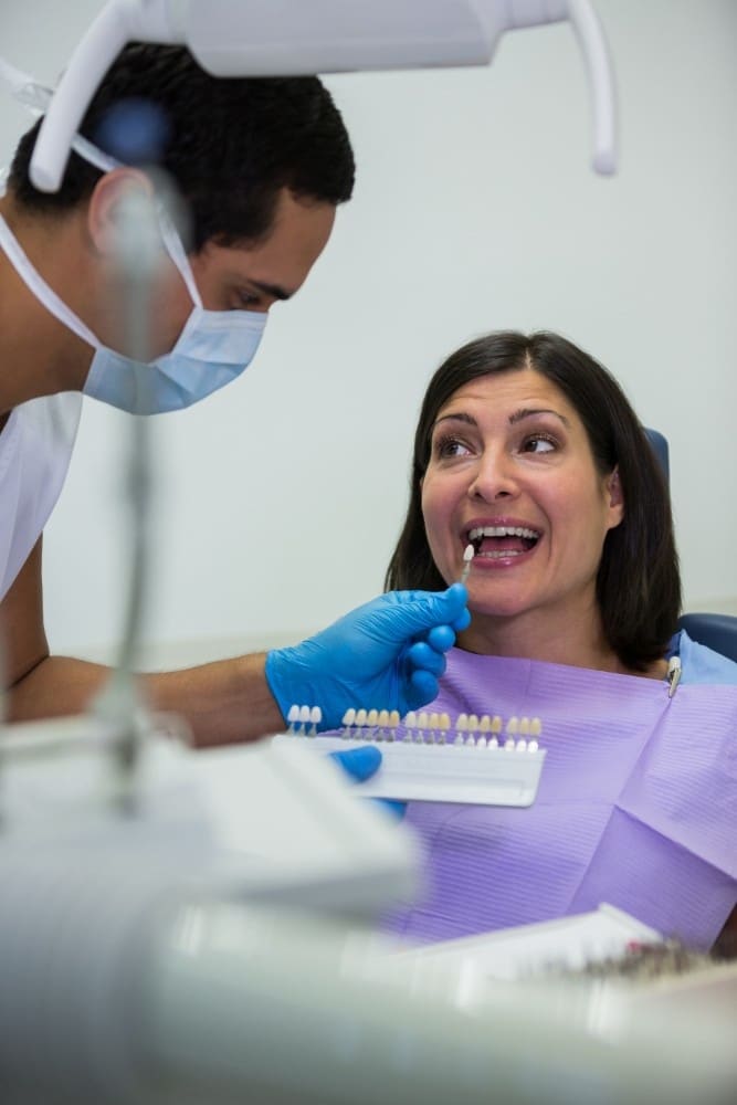 Smiling patient receiving shade matching consultation with dentist during cosmetic dental treatment.