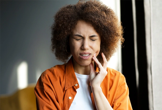 Young woman in pain before TMJ treatment at dental office 