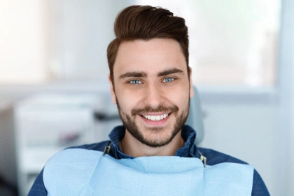 Smiling young man in dental chair getting in cosmetic dentistry 