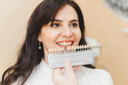 Woman smiling with dental veneers while sitting in the dentist's chair