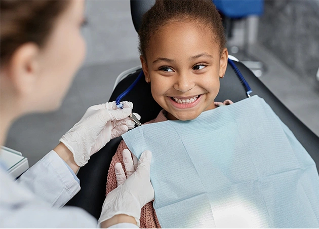 Kid’s smiling in the dentist chair after treatment