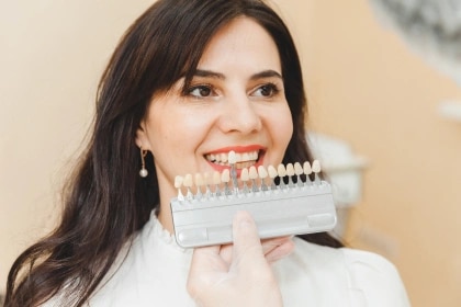 Woman smiling with dental veneers while sitting in the dentist's chair